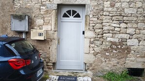 A stone building with a white door, a mailbox, and a car parked in front. - L'écrin de l'abreuvoir – Cozy Ground-Floor Retreat in Marnay Near Besançon (Marnay)