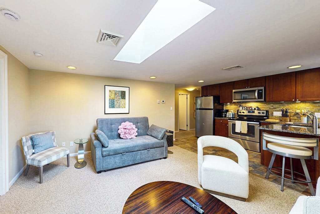 A living room with a sofa, armchairs, a coffee table, and a kitchen area with appliances.