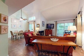 Ein geräumiger Wohnbereich mit Esstisch, Sofa, Fernseher und großen Fenstern.