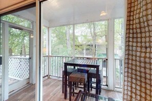 Un portico coperto con tavolo e sedie, vista sull'esterno e un molo di legno.