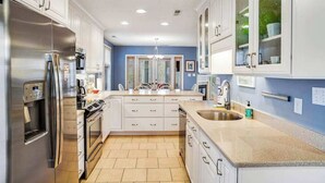 A modern kitchen with white cabinetry, stainless steel appliances, a central island, and a blue accent wall. - Sea Colony Tennis townhouse with board games, & tennis court (Bethany Beach)
