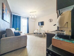 A modern living room with a sofa, dining table, and kitchen area. - Siciliandò by Interhome (Terrasini)