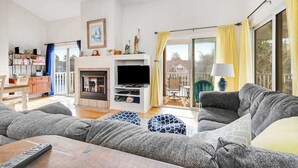 A living room with a fireplace, a television, and a sofa. - Sea Colony Tennis second-floor condo with fireplace, gym, & tennis court (Bethany Beach)