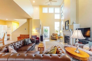 A spacious living room with a large brown leather sofa, a fireplace, and a television. - Sea Colony Tennis house with sauna, pool, gym, & basketball court (Bethany Beach)