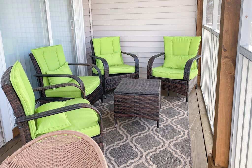 Un balcon agrémenté de meubles en osier et d’un tapis à motifs.