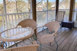 Un espace extérieur abrité, aménagé avec des meubles en osier et une table en verre.