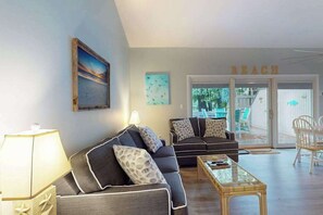 Ein Wohnzimmer mit Sofa, Couchtisch und Lampe. An der Wand hängt ein Gemälde, und ein Schild mit der Aufschrift 'BEACH'.