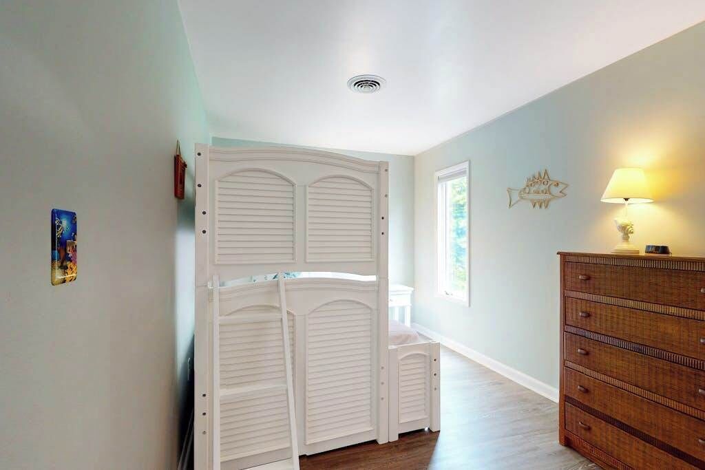 Un couloir avec une armoire blanche, une commode en bois et une lampe fixée au mur.