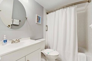 A bathroom with a round mirror, a sink, a toilet, and a shower curtain. - Sea Colony first-floor condo with fast WiFi, central AC & pool/gym access (Bethany Beach)