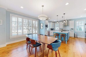 A modern kitchen with a central island, wooden flooring, and pendant lighting. - Coastal Elegance: Retreat Two Blocks from the Sand (Rehoboth Beach)