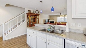 A kitchen with white cabinets, a built-in dishwasher, a double sink, and pendant lighting. - Canal Landing townhouse w/community pool, patio, close to restaurants (Rehoboth Beach)