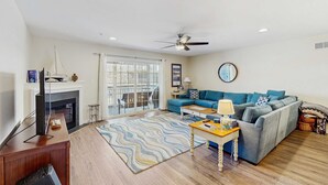 A living room with a fireplace, a sofa, a coffee table, and a television. - Canal Landing townhouse w/community pool, patio, close to restaurants (Rehoboth Beach)