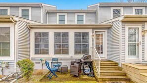 A two-story residential building with a covered patio area, outdoor seating, and a barbecue grill. - Versailles at Eagles Landing townhome with pool & tennis - walk to beach shuttle (Rehoboth Beach)