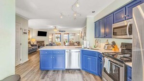 A kitchen with blue cabinets, a stainless steel refrigerator, and a built-in oven. - Versailles at Eagles Landing townhome with pool & tennis - walk to beach shuttle (Rehoboth Beach)