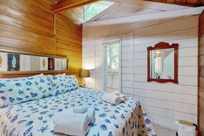 A wooden-paneled room with a bed, a framed picture, a mirror, and a window. - Dewey Beach cottage 1 block from the beach, dog friendly (Dewey Beach)