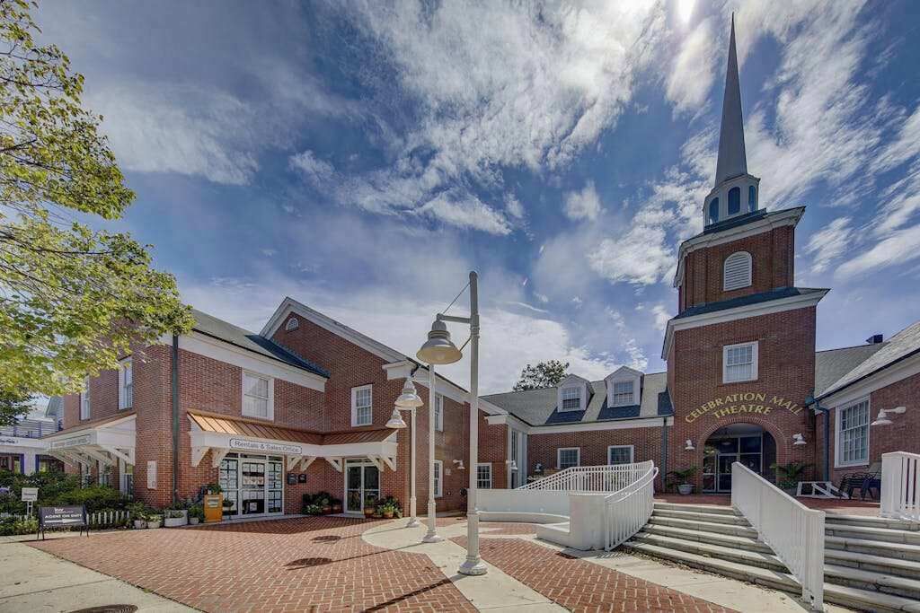 A brick building with a central tower and a sign reading 'Celebration Mall Theatre.'