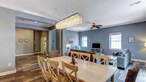Ampla sala de estar com mesa de jantar, cadeiras, sofá e televisão.