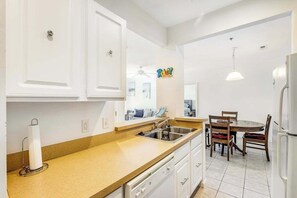 A kitchen with white cabinets, a sink, and a dining area with a table and chairs.