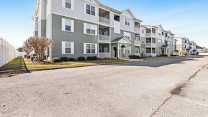A row of multi-story apartment buildings with balconies, a driveway, and a clear sky. - Sandpiper Villages condo with fast WiFi, private patio & more - near the beach (Rehoboth Beach)