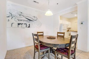 A dining area with a round wooden table, four chairs, and a wall mural.