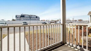 A residential building with a balcony, a parking lot with cars, and a clear sky. - Sandpiper Villages condo with fast WiFi, private patio & more - near the beach (Rehoboth Beach)