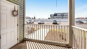 A covered porch with a view of a parking lot and buildings in the background. - Sandpiper Villages condo with fast WiFi, private patio & more - near the beach (Rehoboth Beach)