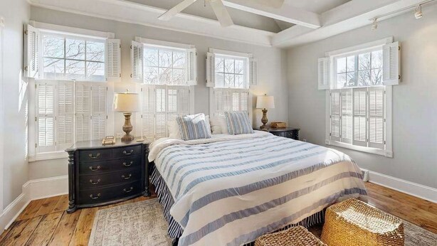 A bedroom with a bed, nightstands, a dresser, a ceiling fan, and windows with shutters. - Town of Lewes house w/deck, balcony, close to beach & restaurants (Lewes)