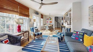 A spacious living room with a large ceiling fan, a dining area, and a staircase leading to an upper level. - Town of Lewes house w/deck, balcony, close to beach & restaurants (Lewes)