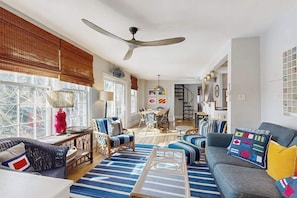 A spacious living room with a large ceiling fan, a dining area, and a staircase leading to an upper level. - Town of Lewes house w/deck, balcony, close to beach & restaurants (Lewes)