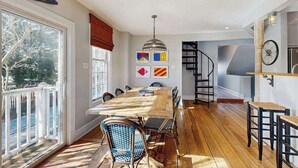 A dining area with a wooden table and chairs, a staircase, and a view of the outdoors. - Town of Lewes house w/deck, balcony, close to beach & restaurants (Lewes)