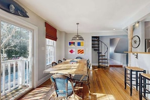 A dining area with a wooden table and chairs, a staircase, and a view of the outdoors. - Town of Lewes house w/deck, balcony, close to beach & restaurants (Lewes)