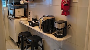 Eine kleine Küche mit Mikrowelle, Kaffeemaschine und einem roten Weihnachtstuch an der Wand.