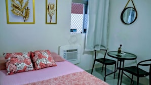 Ein Schlafzimmer mit einem Bett, zwei Kissen, einem Nachttisch, einem Spiegel und einem Fenster mit Vorhängen.