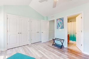 A room with a wooden floor, white doors, a teal rug, and a painting on the wall. - Rehoboth Crossing townhome with pool, trails, EV charger, gym, balcony (Rehoboth Beach)
