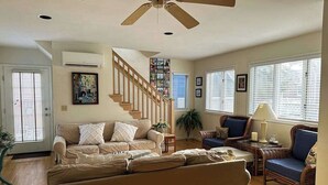 Ein Wohnzimmer mit Sofa, Sesseln, einer Treppe und einem Deckenventilator.