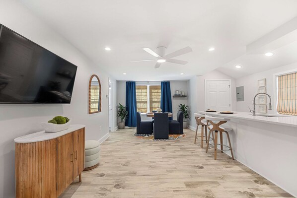 A modern kitchen with a dining area, a TV mounted on the wall, and a ceiling fan. - Dog-friendly Rehoboth Beach cottage steps from the beach & boardwalk with AC (Rehoboth Beach)