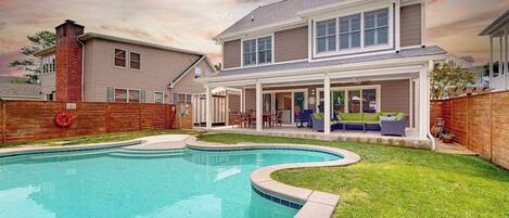A two-story house with a swimming pool, a brick chimney, and a covered patio area.