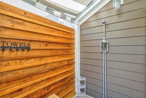 Pared de madera con un perchero y una zona de ducha con un tubo de metal.
