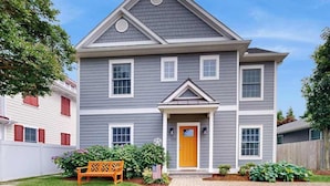 A two-story house with a front porch, a central entrance, and a small garden area with a bench and plants. - Dog-friendly, 2-story home near beach with private outdoor pool, W/D & AC (Rehoboth Beach)
