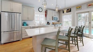 A modern kitchen with stainless steel appliances, a white island, and pendant lighting. - Dog-friendly, 2-story home near beach with private outdoor pool, W/D & AC (Rehoboth Beach)