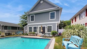 A two-story house with a swimming pool, a patio with chairs, and a small garden. - Dog-friendly, 2-story home near beach with private outdoor pool, W/D & AC (Rehoboth Beach)