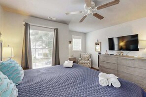 Ein Hotelzimmer mit Bett, Deckenventilator, Fernseher, Kommode und Stuhl.