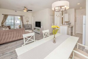 A living room with a sofa, TV, dining table, and chairs.