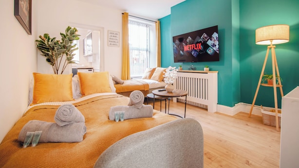Ein modernes Hotelzimmer mit Bett, Sofa, Fernseher, Lampe und Fenster.