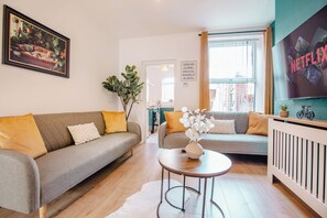 A living room with two sofas, a coffee table, a framed picture, and a TV screen displaying 'NETFLIX'. - Modern Escape Oasis | Free Parking | 14PPL (Sheffield)