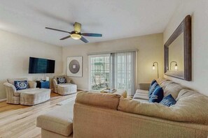 A living room with a ceiling fan, a sofa, a coffee table, and a TV. - 3-story townhouse close to beach & shops w/screened porch, on-site pool & gym (Rehoboth Beach)