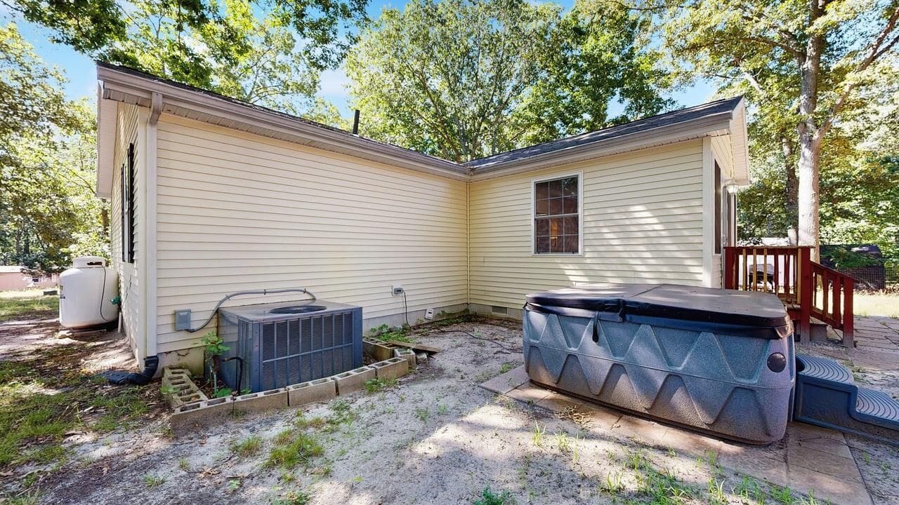 A single-story house with a small porch, a covered outdoor seating area, and a large storage container.