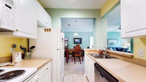 A compact kitchen with white cabinetry, a stove, and a dishwasher. - Sandpiper Village dog-friendly condo with patio, AC & close access to everything (Rehoboth Beach)