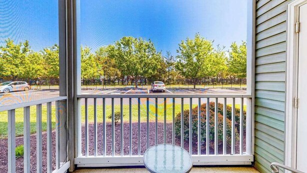 A balcony with a view of a parking lot and trees. - Sandpiper Village dog-friendly condo with patio, AC & close access to everything (Rehoboth Beach)