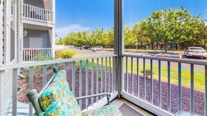 A balcony with a view of a parking lot and trees. - Sandpiper Village dog-friendly condo with patio, AC & close access to everything (Rehoboth Beach)